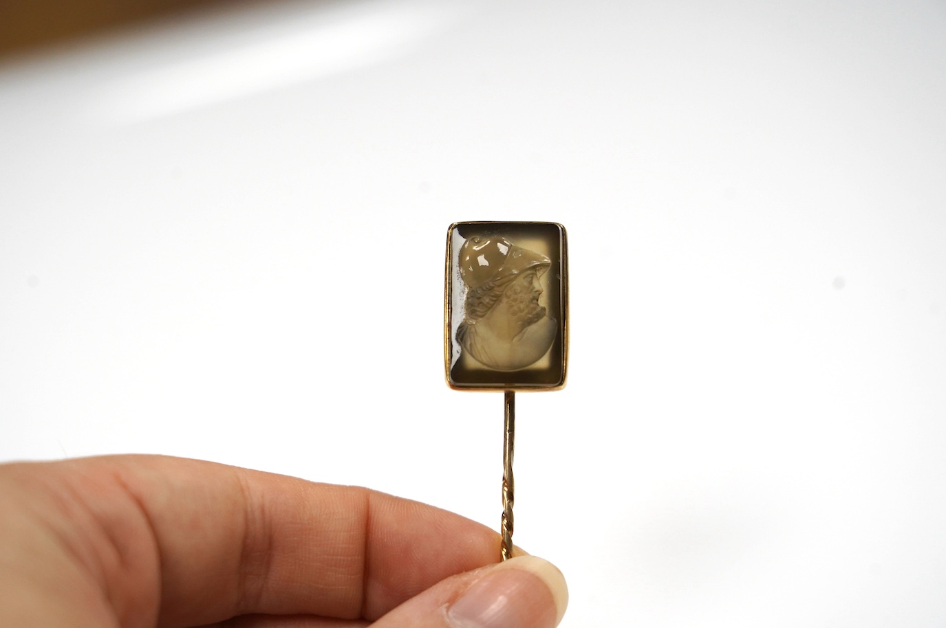 A yellow metal and cameo hardstone set stick pin, 88mm, gross weight 6.9 grams. Condition - poor to fair